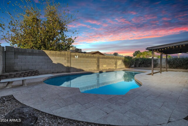 pool at dusk featuring a patio area