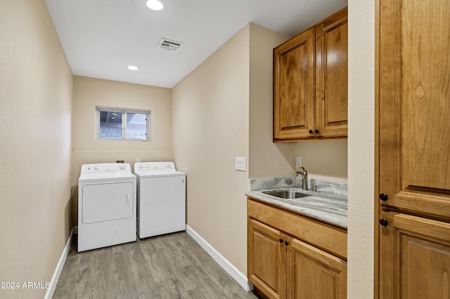 laundry room featuring washer and clothes dryer, cabinets, light wood-type flooring, and sink