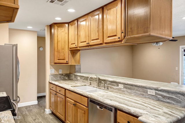 kitchen featuring sink, light stone countertops, stainless steel appliances, and light hardwood / wood-style flooring