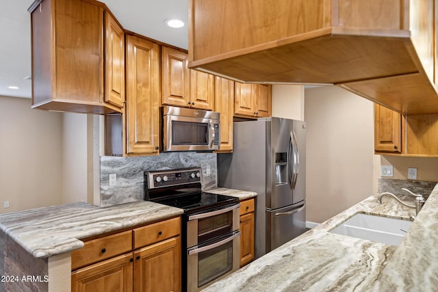 kitchen featuring backsplash, sink, light stone countertops, and stainless steel appliances