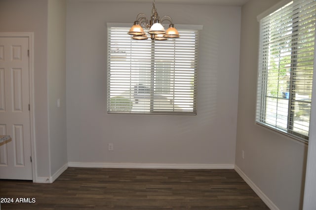 unfurnished dining area featuring dark hardwood / wood-style flooring, a chandelier, and a healthy amount of sunlight