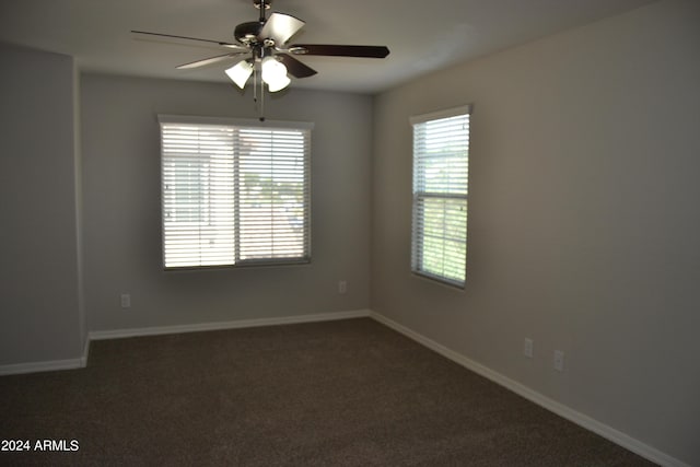 empty room featuring ceiling fan and dark colored carpet