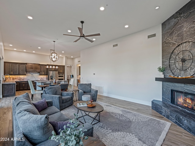 living room with sink, ceiling fan, light hardwood / wood-style flooring, and a fireplace