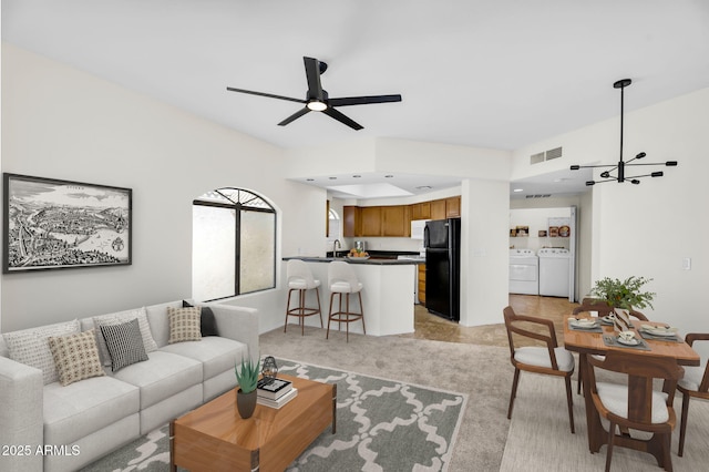 10030 W Indian School Rd Unit 218, Phoenix, AZ 85037 - living area with washing machine and clothes dryer, a ceiling fan, a chandelier, and light colored carpet