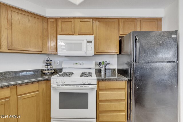 kitchen featuring white appliances and dark stone countertops