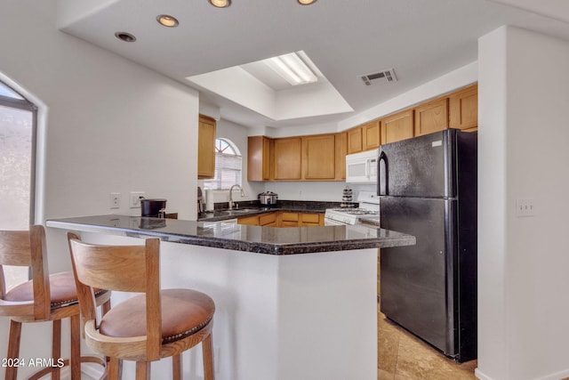 kitchen with dark countertops, visible vents, a kitchen bar, a peninsula, and white appliances