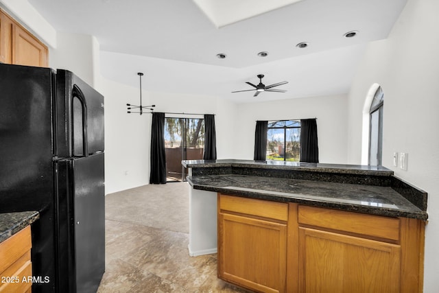 10030 W Indian School Rd Unit 218, Phoenix, AZ 85037 - kitchen with freestanding refrigerator, ceiling fan, dark stone counters, open floor plan, and brown cabinetry