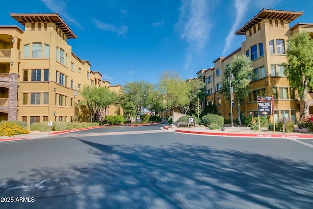 view of asphalt street featuring curbs, street lights, sidewalks, and traffic signs