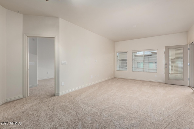 spare room featuring light carpet and baseboards