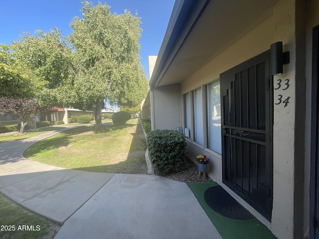exterior space featuring stucco siding and a lawn