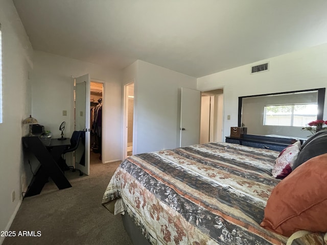 carpeted bedroom featuring a walk in closet, visible vents, a closet, and baseboards