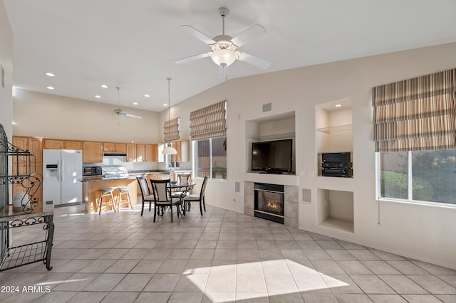 interior space featuring a tile fireplace, plenty of natural light, lofted ceiling, and ceiling fan