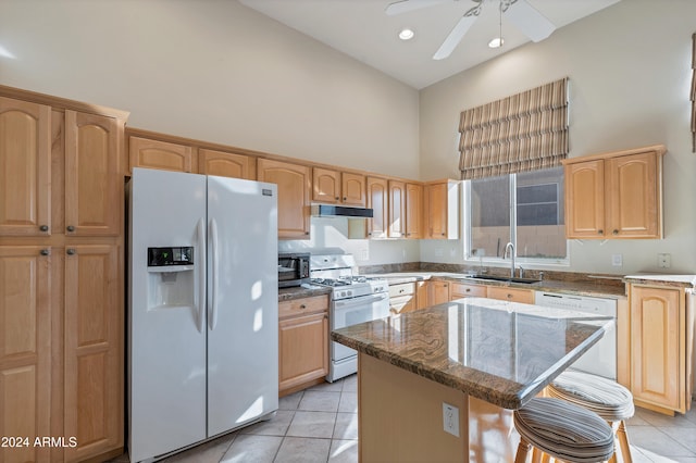 kitchen featuring light tile patterned floors, white appliances, a kitchen island, and sink