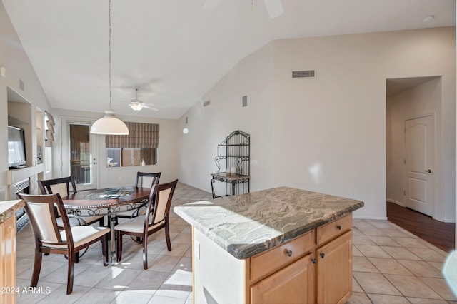 kitchen featuring ceiling fan, a center island, pendant lighting, vaulted ceiling, and light tile patterned floors