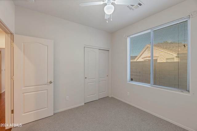 unfurnished bedroom featuring light colored carpet, a closet, and ceiling fan