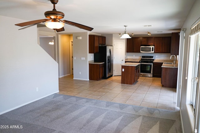 kitchen featuring stainless steel appliances, ceiling fan, sink, a center island, and light tile patterned flooring