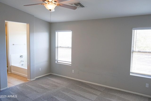 unfurnished bedroom featuring ceiling fan, light colored carpet, and ensuite bath