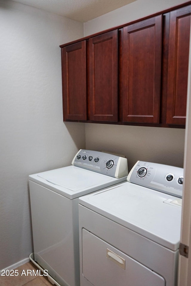 laundry room featuring cabinets, washing machine and dryer, and tile patterned floors