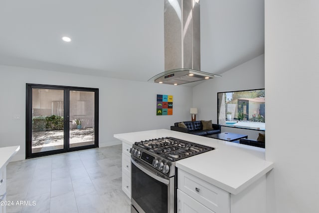 kitchen featuring wall chimney exhaust hood, gas range, vaulted ceiling, and white cabinets