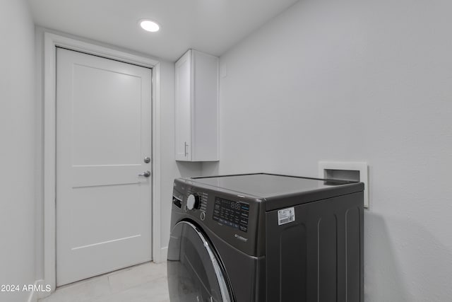 laundry area featuring cabinets, washer / dryer, and light tile patterned flooring