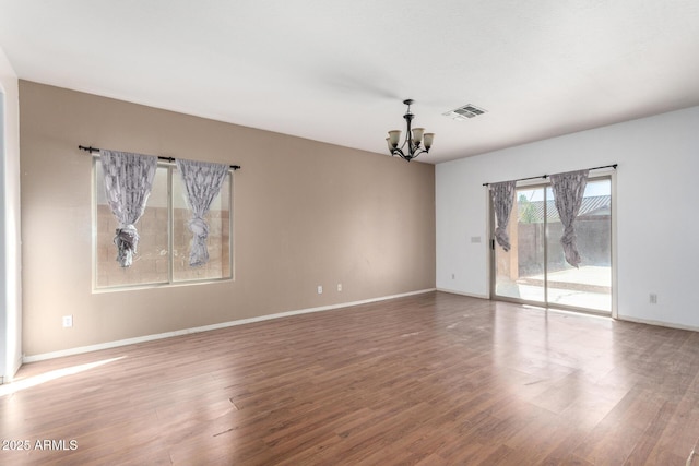 empty room featuring hardwood / wood-style flooring and an inviting chandelier