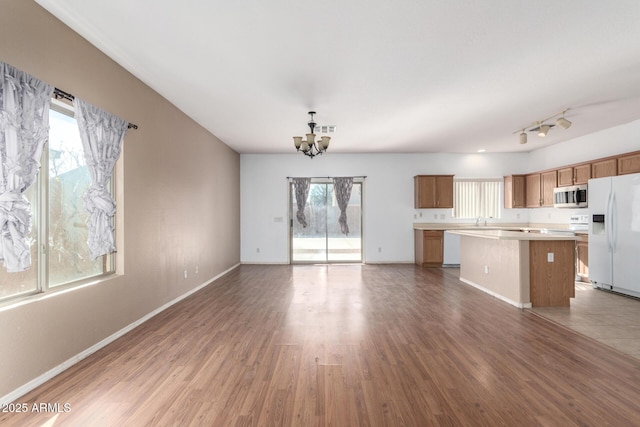 kitchen featuring white fridge with ice dispenser, a center island, a notable chandelier, and a healthy amount of sunlight