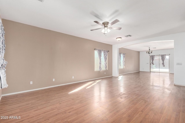 spare room with light wood-type flooring and ceiling fan with notable chandelier