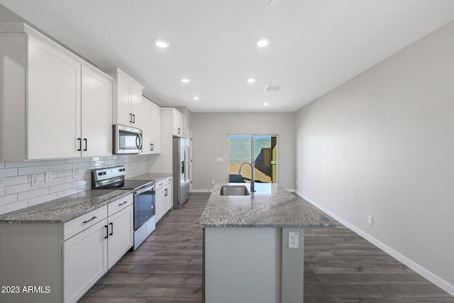 kitchen featuring a kitchen island with sink, dark wood-type flooring, white cabinets, appliances with stainless steel finishes, and light stone counters