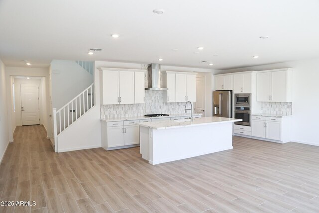 kitchen with a kitchen island with sink, dark brown cabinets, appliances with stainless steel finishes, a breakfast bar area, and light hardwood / wood-style floors