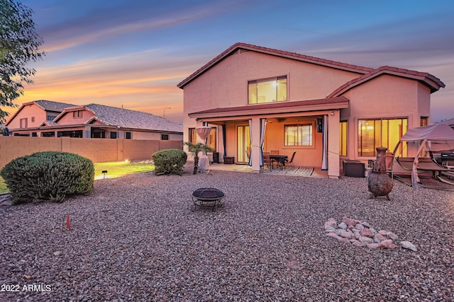 3900 S Velero St, Chandler, AZ 85249 - back of house at dusk featuring a tile roof, fence, an outdoor fire pit, a patio, and stucco siding
