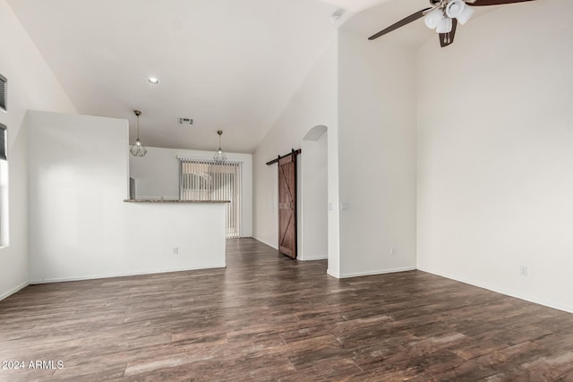 unfurnished living room featuring lofted ceiling, a barn door, ceiling fan, and dark wood-type flooring