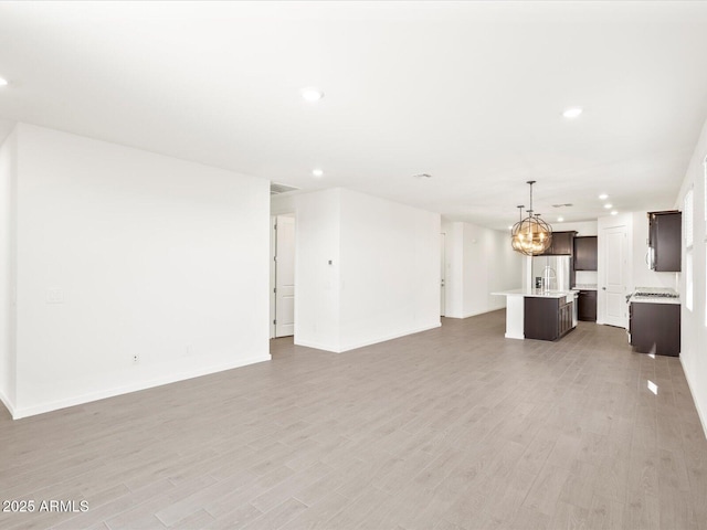 5537 S 246th Ave, Buckeye, AZ 85326 - unfurnished living room featuring recessed lighting, light wood-style flooring, and a chandelier