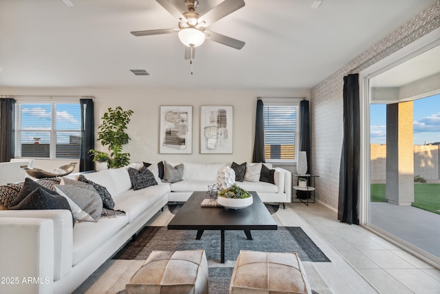 living room with a healthy amount of sunlight, light tile patterned floors, visible vents, and wallpapered walls