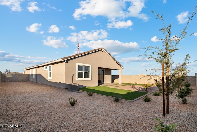 rear view of house with central air condition unit, a fenced backyard, a patio, and stucco siding