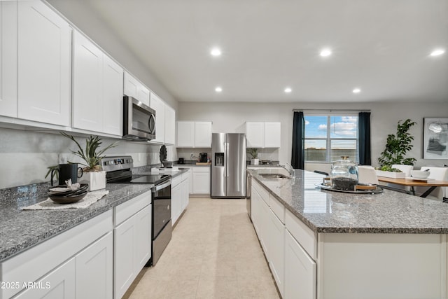 kitchen featuring stainless steel appliances, recessed lighting, a kitchen island with sink, white cabinets, and a sink