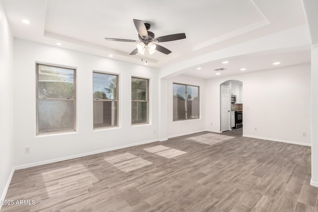 3444 E Flamingo Ct, Gilbert, AZ 85297 - unfurnished room featuring a tray ceiling, a ceiling fan, recessed lighting, light wood-style floors, and arched walkways