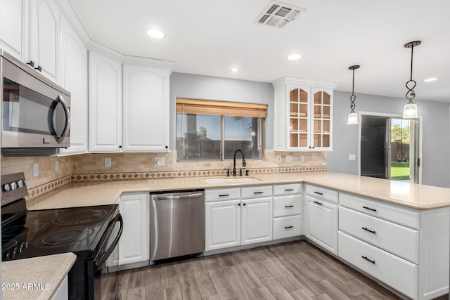 3444 E Flamingo Ct, Gilbert, AZ 85297 - kitchen featuring appliances with stainless steel finishes, a peninsula, glass insert cabinets, decorative backsplash, and recessed lighting