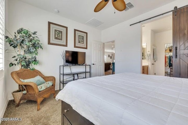 bedroom featuring ensuite bath, a barn door, light carpet, a closet, and ceiling fan