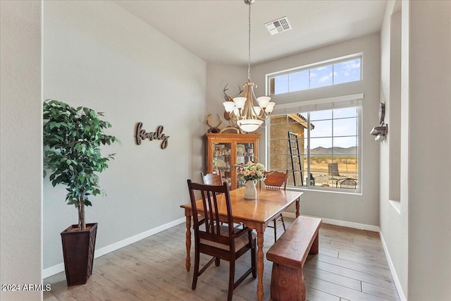 dining space with hardwood / wood-style floors, plenty of natural light, and a chandelier