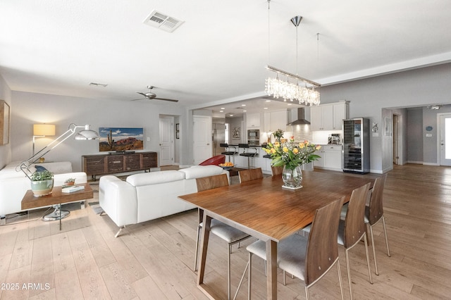 dining space with ceiling fan, light wood finished floors, and visible vents