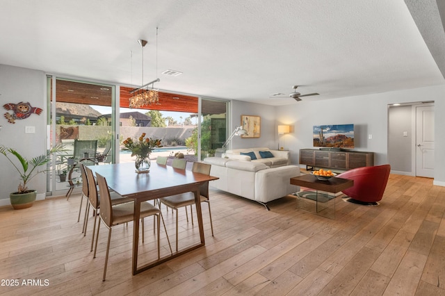 dining space featuring baseboards, visible vents, a textured ceiling, light wood-type flooring, and floor to ceiling windows