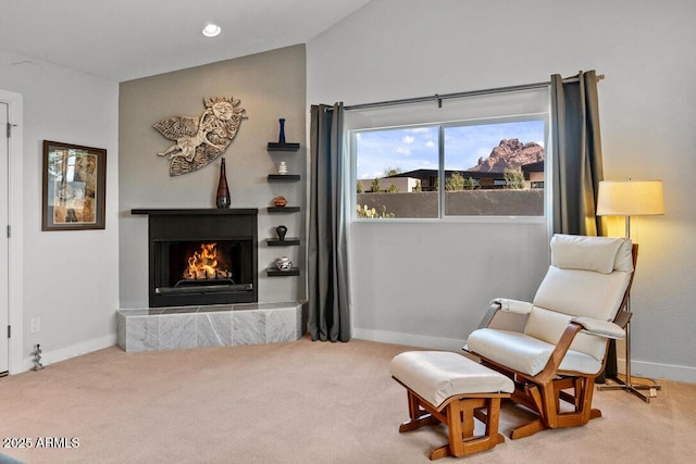 living area featuring vaulted ceiling, a lit fireplace, carpet flooring, and baseboards