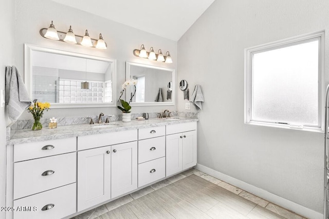 bathroom with double vanity, a wealth of natural light, vaulted ceiling, and a sink