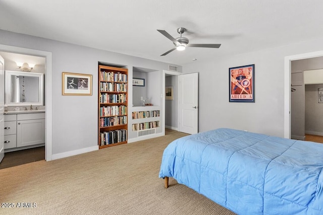 bedroom featuring carpet floors, visible vents, ensuite bathroom, a sink, and baseboards