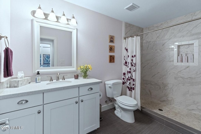 bathroom featuring visible vents, a tile shower, vanity, and toilet