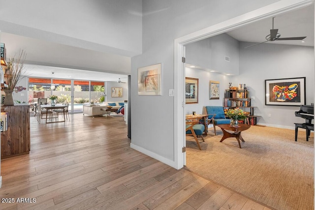 hall with high vaulted ceiling, baseboards, and hardwood / wood-style flooring