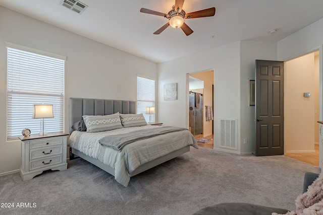 bedroom with ensuite bath, light carpet, and ceiling fan