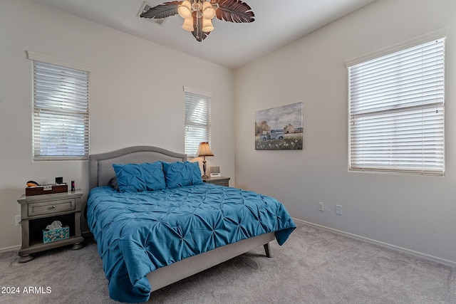 carpeted bedroom featuring multiple windows and ceiling fan