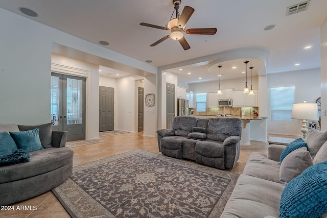 tiled living room featuring ceiling fan, a healthy amount of sunlight, and french doors