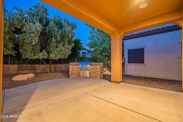 patio terrace at dusk with a grill and exterior kitchen